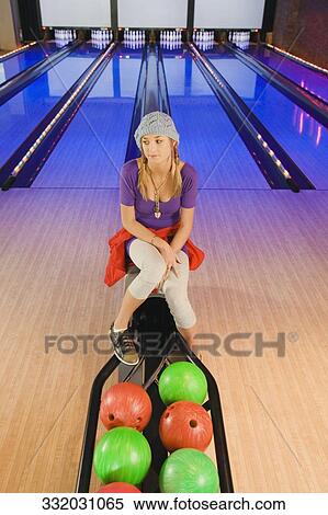 Stock Photography - Teenage girl sitting in a bowling alley and thinking. Fotosearch