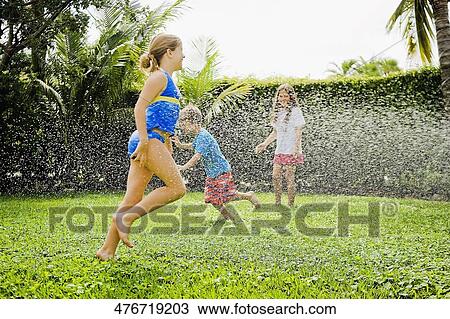 Stock Image - Three friends playing in a lawn. Fotosearch