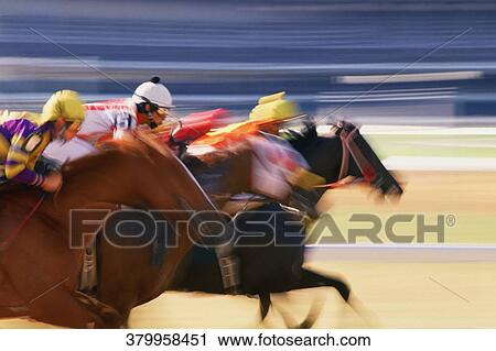 Stock Image - Three jockeys riding their horses on a running track. Fotosearch