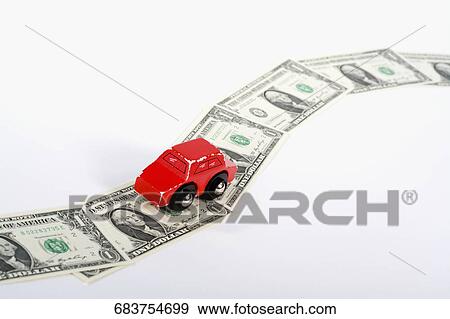 Stock Photo - Toy car moving on a US paper currency road. Fotosearch