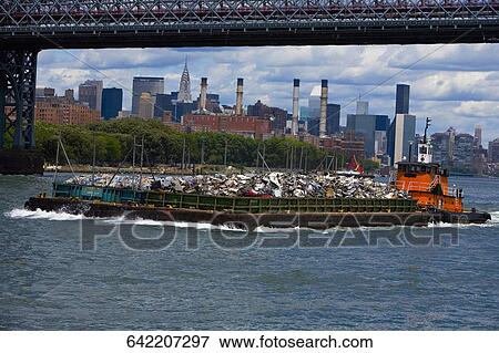 Stock Photo - Tugboat carrying garbage in the river, Hudson River, Manhattan, New York City, New York State, USA. Fotosearch