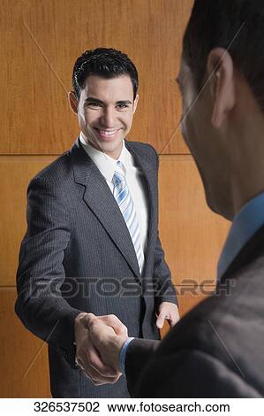 Two businessmen shaking hands and smiling View Large Photo Image Stock Image - Two businessmen shaking hands and smiling. Fotosearch