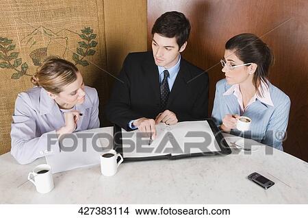 Two businesswomen and a businessman discussing in a cafe View Large Photo Image Picture - Two businesswomen and a businessman discussing in a cafe. Fotosearch