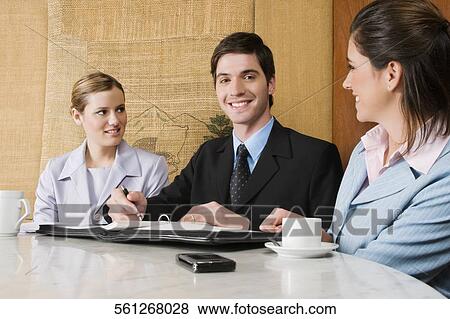 Stock Photo - Two businesswomen and a businessman discussing in a cafe. Fotosearch