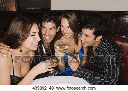 Stock Photo - Two couples holding glasses of wine and smiling in a bar. Fotosearch