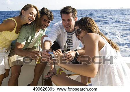 Stock Photography - Two couples looking at a digital camera and smiling. Fotosearch