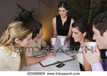 Stock Photo - Two couples sitting in a cafe and smiling. Fotosearch