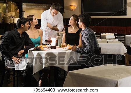 Two couples with a male chef in a restaurant View Large Photo Image Stock Image - Two couples with a male chef in a restaurant. Fotosearch