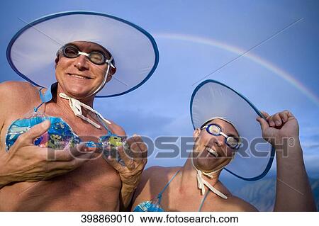 Stock Image - Two gay men wearing bikini tops and dancing. Fotosearch