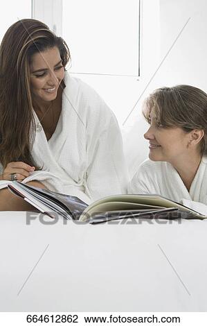Two mid adult women talking to each other on the bed View Large Photo Image Stock Image - Two mid adult women talking to each other on the bed. Fotosearch