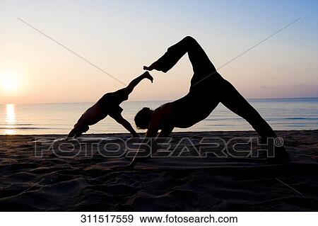 Stock Photo - Two people practicing yoga on the beach. Fotosearch