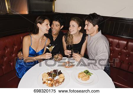 Stock Photography - Two young couples sitting at a table in a restaurant and smiling. Fotosearch