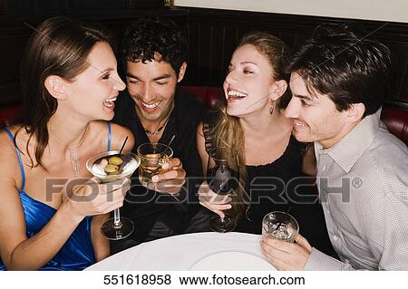 Two young couples sitting at a table and enjoying cocktail View Large Photo Image Stock Photo - Two young couples sitting at a table and enjoying cocktail. Fotosearch