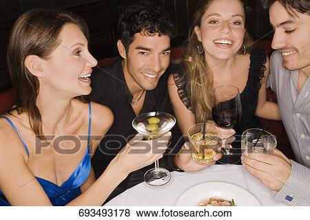 Two young couples sitting at a table and enjoying cocktail View Large Photo Image Stock Photo - Two young couples sitting at a table and enjoying cocktail. Fotosearch