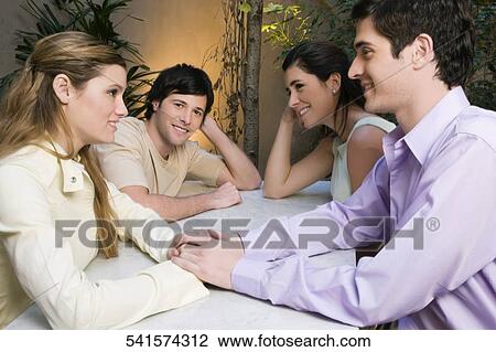 Stock Image - Two young couples sitting in a cafe and smiling. Fotosearch