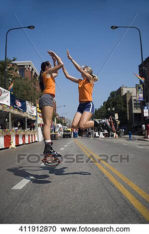 Two young women giving high-five to each other and jumping on the road View Large Photo Image Stock Image - Two young women giving high-five to each other and jumping on the road. Fotosearch