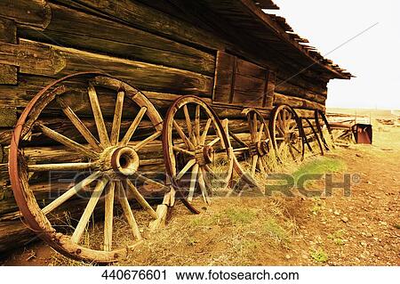 Stock Image - Wagon wheels leaning against the wall of an abandoned building, Old Trail Town, Cody, Wyoming, USA. Fotosearch