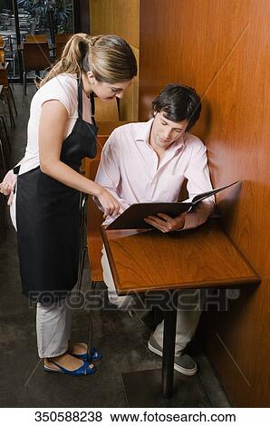 Waitress showing menu to a customer in a cafe View Large Photo Image Stock Photo - Waitress showing menu to a customer in a cafe. Fotosearch