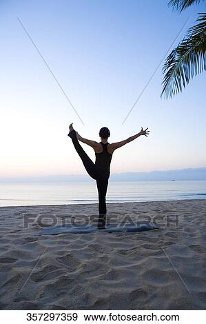 Stock Photo - Woman practicing yoga on the beach. Fotosearch