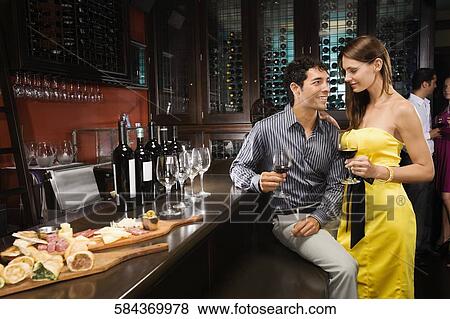 Young couple drinking wine at a bar counter and smiling View Large Photo Image Stock Photo - Young couple drinking wine at a bar counter and smiling. Fotosearch