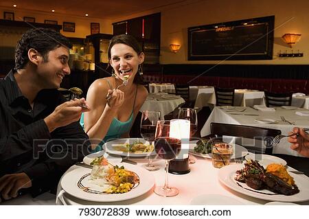 Young couple eating food in a restaurant View Large Photo Image Stock Photo - Young couple eating food in a restaurant. Fotosearch
