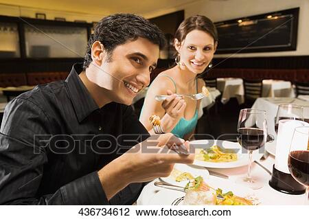 Young couple eating food in a restaurant and smiling View Large Photo Image Stock Image - Young couple eating food in a restaurant and smiling. Fotosearch