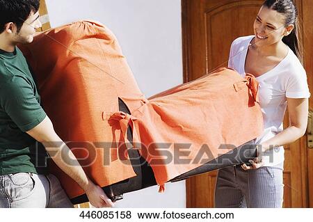 Young couple holding a chair and smiling View Large Photo Image Stock Photo - Young couple holding a chair and smiling. Fotosearch