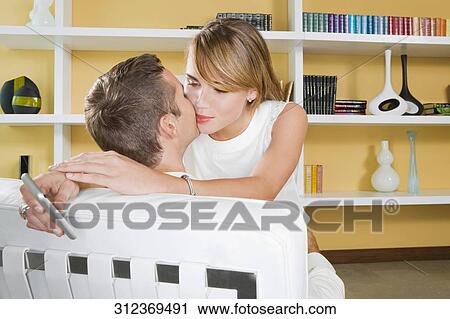 Young couple kissing each other and young woman holding a mobile phone View Large Photo Image Stock Image - Young couple kissing each other and young woman holding a mobile phone. Fotosearch