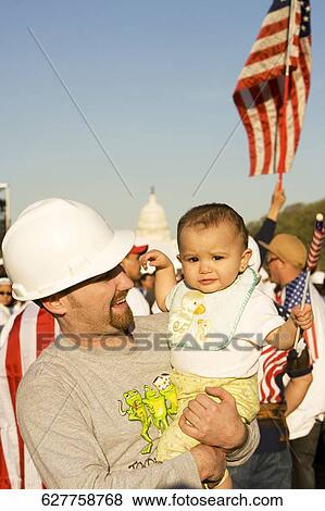 Young man carrying his son and smiling View Large Photo Image Stock Photo - Young man carrying his son and smiling. Fotosearch