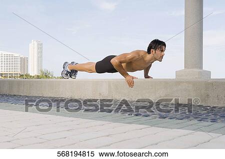 Young man doing push ups on the ledge View Large Photo Image Stock Photography - Young man doing push ups on the ledge. Fotosearch