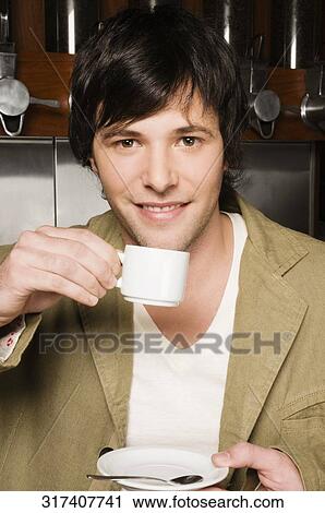 Young man drinking coffee in a cafe View Large Photo Image Stock Image - Young man drinking coffee in a cafe. Fotosearch