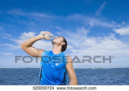 Young man drinking water from a water bottle View Large Photo Image Picture - Young man drinking water from a water bottle. Fotosearch