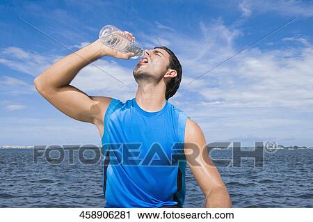 Young man drinking water from a water bottle View Large Photo Image Stock Image - Young man drinking water from a water bottle. Fotosearch