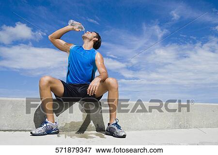 Stock Photo - Young man drinking water from a water bottle. Fotosearch