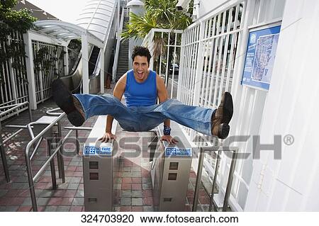 Young man jumping over the ticket barriers View Large Photo Image Stock Image - Young man jumping over the ticket barriers. Fotosearch