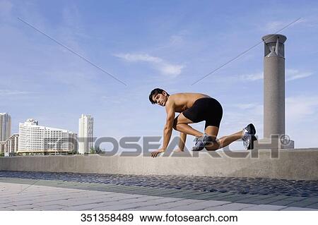 Young man preparing for running on the ledge View Large Photo Image Stock Photo - Young man preparing for running on the ledge. Fotosearch