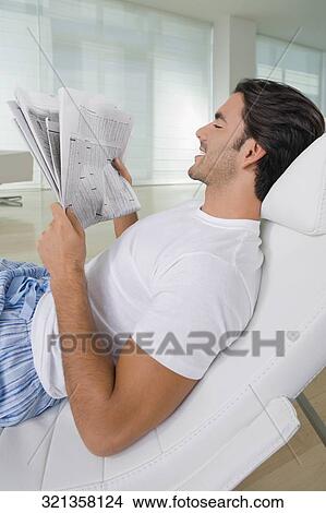 Picture - Young man reading a newspaper. Fotosearch