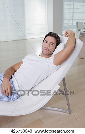 Young man resting on a reclining chair View Large Photo Image Stock Image - Young man resting on a reclining chair. Fotosearch