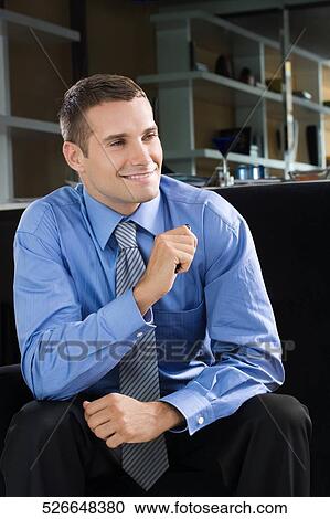 Stock Image - Young man sitting and smiling. Fotosearch