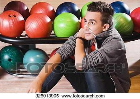 Young man sitting in a bowling alley and thinking View Large Photo Image Stock Photography - Young man sitting in a bowling alley and thinking. Fotosearch