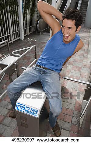 Young man sitting on a barrier and smiling View Large Photo Image Stock Photo - Young man sitting on a barrier and smiling. Fotosearch