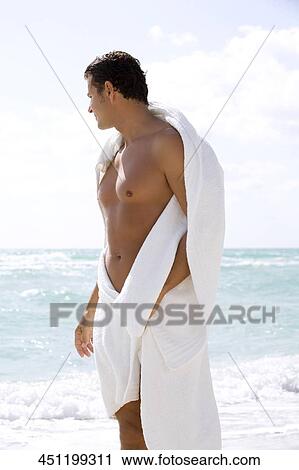 Stock Image - Young man standing on the beach. Fotosearch