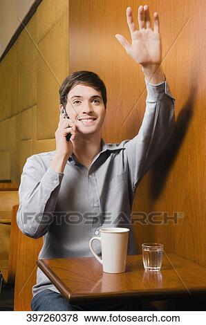 Young man talking on a mobile phone in a cafe View Large Photo Image Stock Photo - Young man talking on a mobile phone in a cafe. Fotosearch