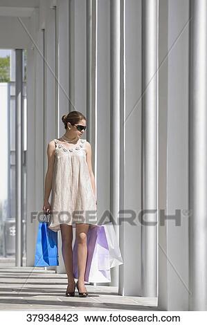 Stock Image - Young woman carrying shopping bags. Fotosearch