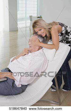 Stock Image - Young woman covering eyes of her grandfather. Fotosearch