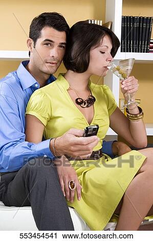 Young woman drinking cocktail and sitting with a mid adult man on a chair View Large Photo Image Stock Image - Young woman drinking cocktail and sitting with a mid adult man on a chair. Fotosearch