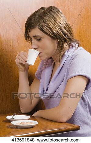 Young woman drinking coffee in a cafe View Large Photo Image Stock Photo - Young woman drinking coffee in a cafe. Fotosearch