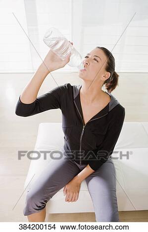 Young woman drinking water from a water bottle View Large Photo Image Picture - Young woman drinking water from a water bottle. Fotosearch
