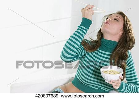 Young woman eating noodles View Large Photo Image Stock Photo - Young woman eating noodles. Fotosearch