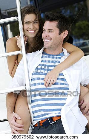 Young woman embracing a mid adult man from behind and smiling View Large Photo Image Stock Image - Young woman embracing a mid adult man from behind and smiling. Fotosearch